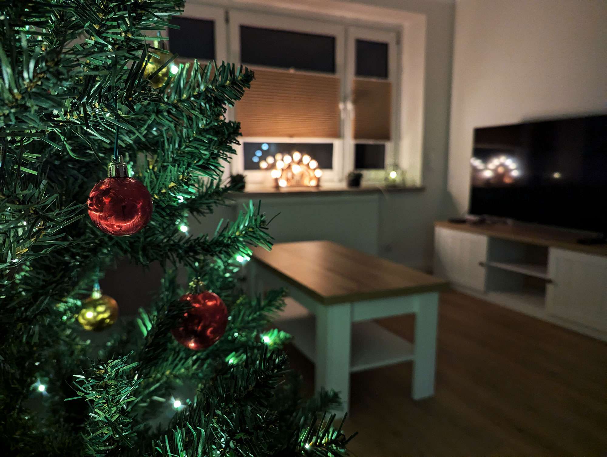 Geschmückter Weihnachtsbaum und Schwibbogen im Hintergrund